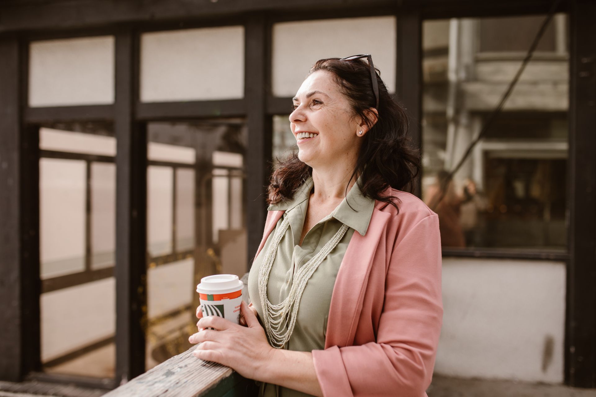 Woman holding a coffee, looking into the distance