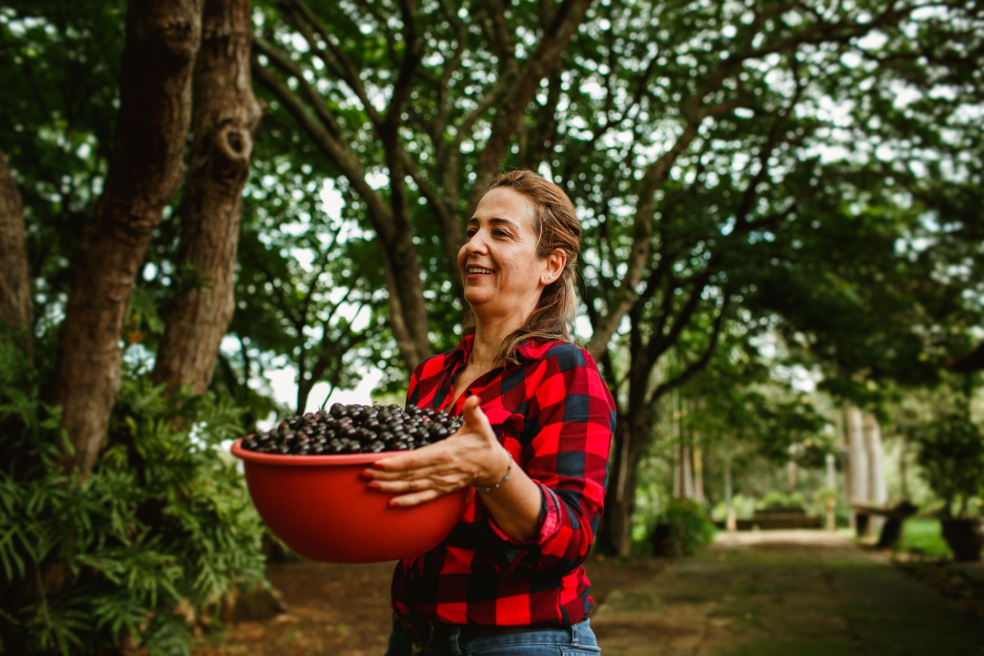 Woman smiling outdoors, holding a bowl of berries