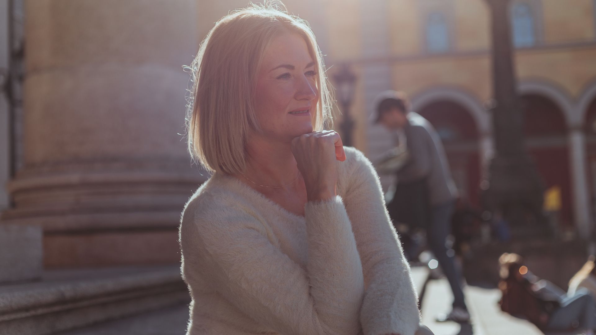 Woman looking thoughtfully into the distance on a sunny street